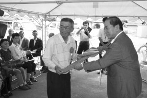 佐藤市長から鍵のレプリカを手渡される入居者の佐藤壽さん(左)