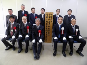 松尾局長（前列右から２人目）ら関係者が看板掲示式で記念撮影した